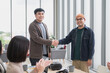 © PhugunStock - Happy Asian male businessman holding hands, looking at camera, brainstorming, talking about analysis, innovation and collaboration. Online business, sales techniques, strategic planning