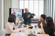 © PhugunStock - Asian male businessman standing explaining meeting, smiling happily and brainstorming, discussing analysis, innovation, collaboration. online business Modern sales techniques and strategic planning