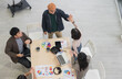 © PhugunStock - Top view: Happy Asian businessmen and women, holding hands, brainstorming and talking about analysis, innovation, and collaboration. Online business, sales techniques, strategic planning