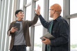 © PhugunStock - Asian male businessman Tag a friend's hand happy smile Holding a tablet, talking about analytics, innovation, and collaboration. Online business, sales techniques, strategic planning