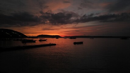 Poster - Serene sunset over calm sea with silhouetted boats.