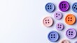 © VANATSANUN - Colorful buttons in various shades arranged on a white background, perfect for crafts and sewing projects.