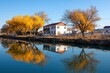 © Outkast - Autumn trees mirroring on river, house in background, clear sky, scenic location