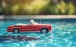 © your_inspiration - Red toy convertible car floats on pool water during sunny afternoon