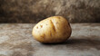 © ABX - A single raw potato on a plain surface, earthy and natural