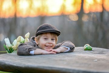 Wall Mural - Beautiful stylish toddler child, boy, playing with Easter decoration in the park, springtime