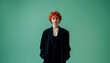 © Evgenii Starkov - Stylish woman with short curly red hair in a black blazer posing against a green background.