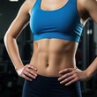 © Over View - Strong and Fit Woman Displaying Toned Abs in Sportswear at the Gym
