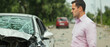 © Krit Kritchaya - Man standing next to damaged car, looking concerned after accident, house and car insurance concepts.