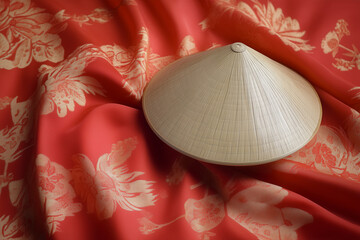 A Vietnamese conical hat (nón lá) resting on a silk ao dai dress, isolated on a solid color background.