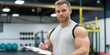 © Andrii Zastrozhnov - A man is writing on a clipboard in a gym. He is wearing a grey shirt and has a beard