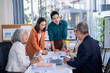 © Wasana - A group of people are gathered around a table with a whiteboard