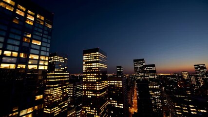 Poster - Dusk envelops a vibrant city skyline, casting a warm glow on illuminated office buildings as night descends, creating a captivating urban panorama in slow motion