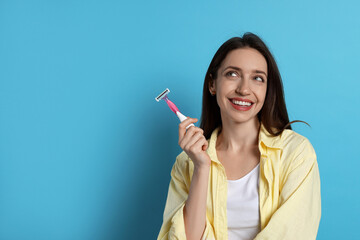 Canvas Print - Happy woman with razor on light blue background, space for text. Hair removal tool