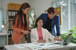 © amnaj - Asian businesspeople discussing and working together using tablet and paperwork showing statistical data in office