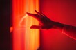 © somchaichoosiri - Persons hand reaching towards a bright red light in a dark environment