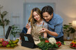 © amnaj - Asian couple cooking following online recipe on tablet