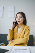 © amnaj - Businesswoman Engaged in Phone Conversation at Office Desk