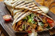© Y_Malashkevych - Close-up of a delicious shawarma wrap filled with tender grilled chicken vibrant fresh vegetables and a drizzle of creamy sauce elegantly presented on a rustic wooden table