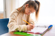 © Louis-Paul Photo - homework and school concept - smiling teen student girl with book writing to notebook at home
