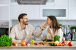 © Dejan - A joyful couple engages in cooking, sharing a light moment while surrounded by fresh vegetables in a bright kitchen.