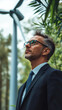 © Michael - Confident businessman wearing suit and tie looking up at wind turbine, promoting renewable energy and green economy
