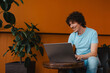 © ADDICTIVE STOCK - Young man with curly hair and laptop in a cozy setting