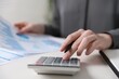 © New Africa - Budget. Woman with paperwork and calculator at white desk indoors, closeup