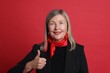 © New Africa - Senior woman showing thumbs up on red background