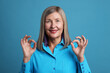 © New Africa - Senior woman showing okay gesture on blue background
