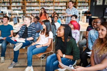 Poster - Diverse group of students in a library, smiling and attentive. Students of various ethnicities, engaged in learning. Library setting with students. Diverse students in library, education concept.