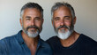 © IA Tuga - A close-up portrait of two middle-aged twin brothers with gray beards, smiling warmly at the camera