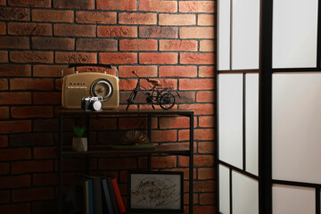 Poster - shelving unit with different decor, radio receiver and camera near brick wall