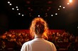 © talkative.studio - Woman attends a performance in theatre; audience watches play; lights in the background