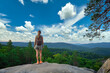 © bilanol - Young woman hiking alone on mountain footpath. Female hiker enjoying view of summer nature on wilderness trail. Active way of life concept