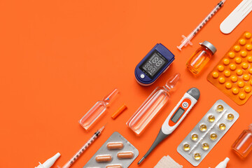 Wall Mural - Composition with pulse oximeter, thermometer and medicines on orange background