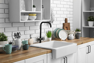 Wall Mural - Wooden kitchen counter with sink, clean dishes and shelving unit hanging on light brick wall