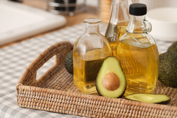 Canvas Print - Bottles of fresh oil and wicker tray with avocados on kitchen counter