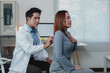 © Phimwilai - Asian male doctor using stethoscope examining female patient's lungs during medical appointment in hospital office, demonstrating healthcare and medical consultation