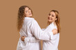 © Pixel-Shot - Beautiful women in white shirts hugging on brown background, back view. Women's History Month