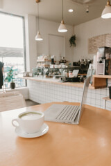 Matcha latte and laptop on wooden table in a bright modern cafe