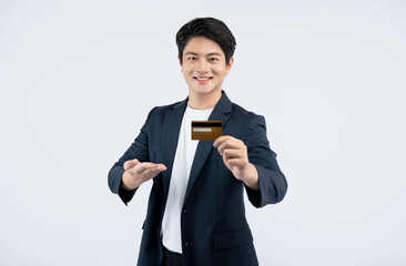 Wall Mural - Portrait of young Asian business man holding bank card and posing on white background