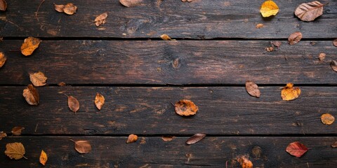 Poster - Autumn leaves in shades of orange and yellow scattered across a dark aged wooden table with knots and texture creating a rustic background