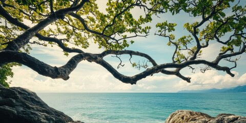 Fototapete - Tropical seascape with intricate tree branches and vibrant green leaves framing a serene blue ocean under a bright sky, ample negative space.