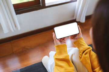 Wall Mural - top view mockup image of a woman holding mobile phone with blank desktop screen while sitting in bed