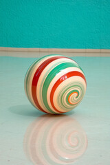 Aufkleber - Abstract striped sphere in layered emerald and ruby bands, gently rotating in midair above a glossy