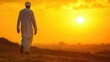 © DailyStock - Arabian man walking in the desert at sunrise, rear view, vast sand dunes, golden light, copy space for Islamic, Ramadan, and Eid banner or poster