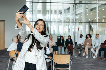 Wall Mural - female business speaker taking selfie with audience during a seminar