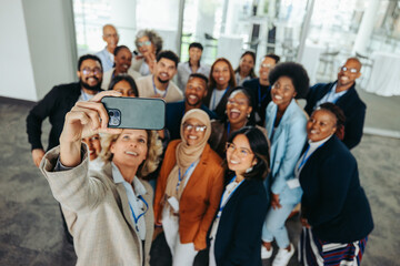 Wall Mural - diverse group of business professionals taking a selfie at a corporate event