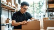 © Chayanin Wongpracha - young man packing boxes in warehouse